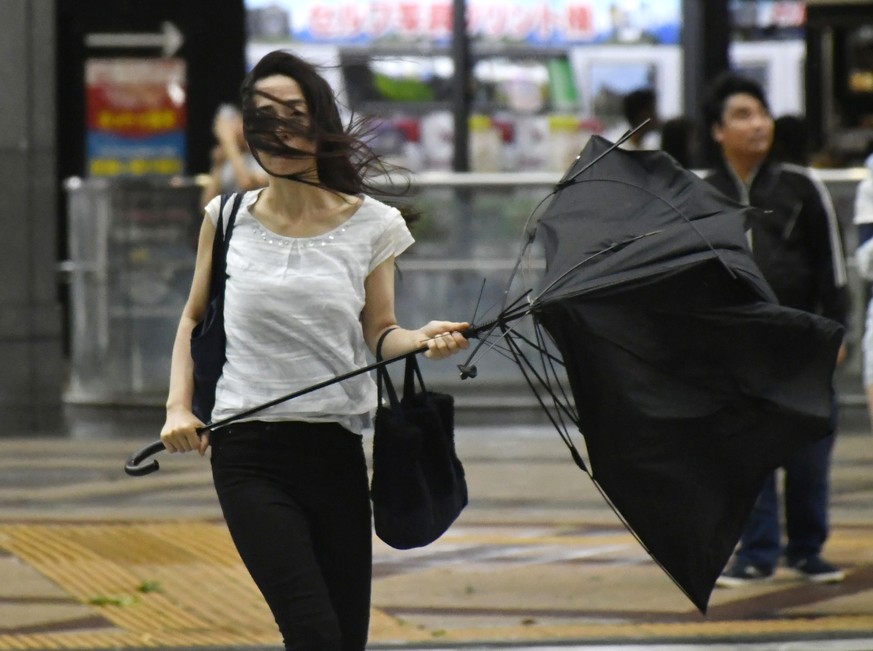 A woman holds broken umbrella as a powerful typhoon hits Osaka, western Japan, Tuesday, Sept. 4, 2018. A powerful typhoon blew through western Japan on Tuesday, causing heavy rain to flood the region& ...