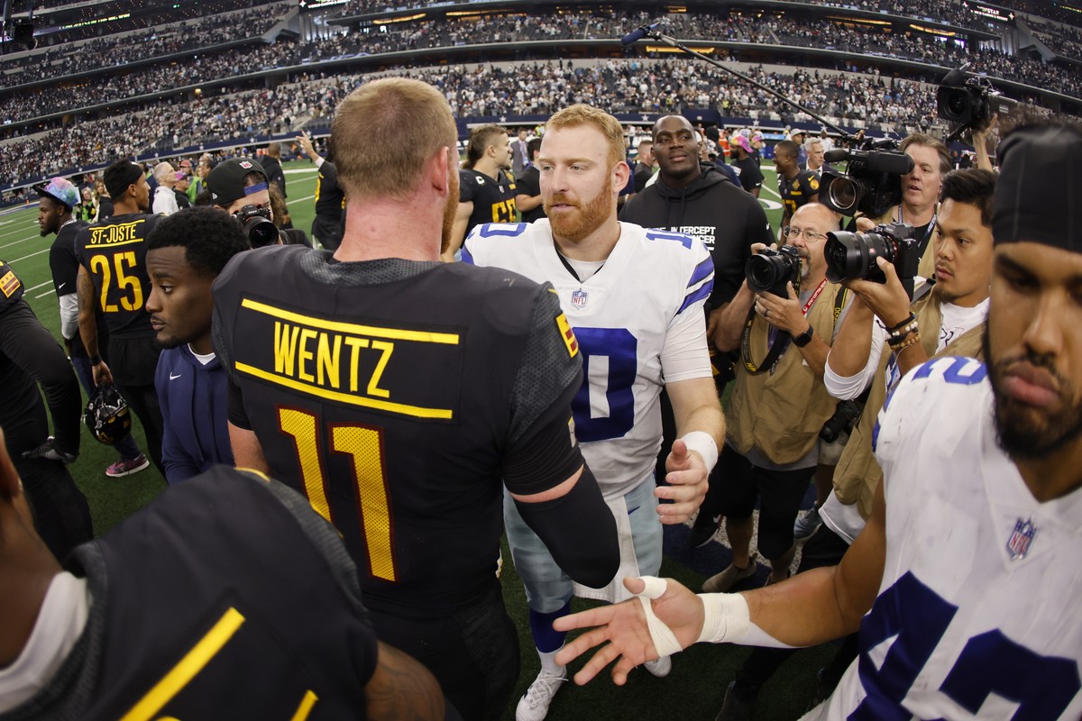Washington Commanders' Carson Wentz (11) and Dallas Cowboys' Cooper Rush, center right, greet each other after their team's NFL football game in Arlington, Texas, Sunday, Oct. 2, 2022.  ...