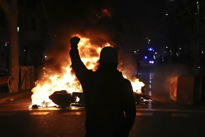 A protestors raises his fist at police across a burning barricade during clashes between protestors and police in Barcelona, Spain, Tuesday, Oct. 15, 2019. Thousands of Catalan separatists are protest ...