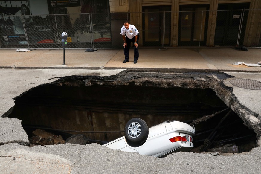 A St. Louis police officer looks over a large hole in 6th Street, Thursday, June 29, 2017, in St. Louis, that swallowed a Toyota Camry between Olive and Locust Streets. It isn&#039;t immediately clear ...