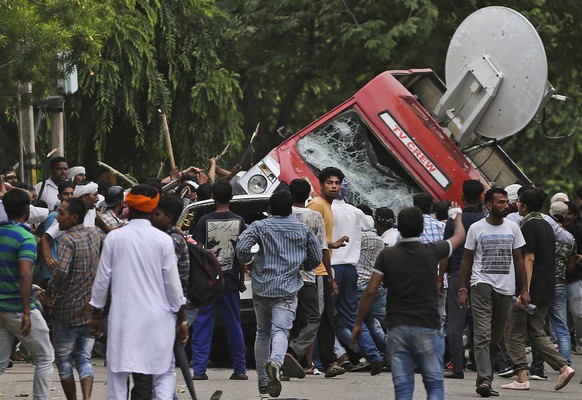 Dera Sacha Sauda sect members overturn an OB van on the streets of Panchkula, India, Friday, Aug. 25, 2017. Deadly riots have broken out in a north Indian town after a court convicted their guru, who  ...