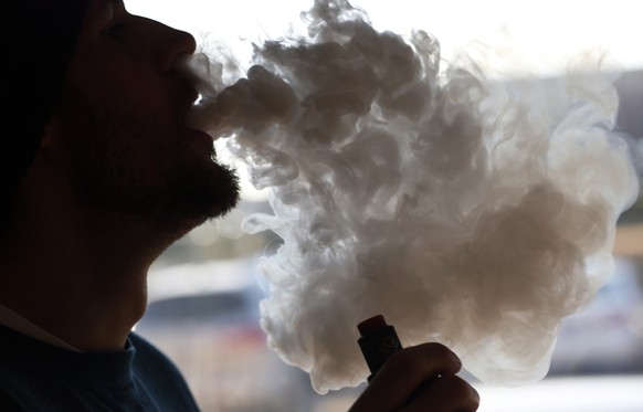 FILE - In this Friday, Jan. 18, 2019 file photo, a customer blows a cloud of smoke from a vape pipe at a local shop in Richmond, Va. Although e-cigarettes aren’t considered as risky as regular cigaret ...
