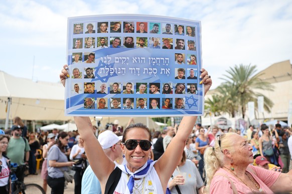 epa12441285 A woman holds a placard with photos of Israeli hostages that reads in Hebrew, &#039;The Merciful One will raise up for us the fallen tabernacle of David,&#039; during a celebration after a ...