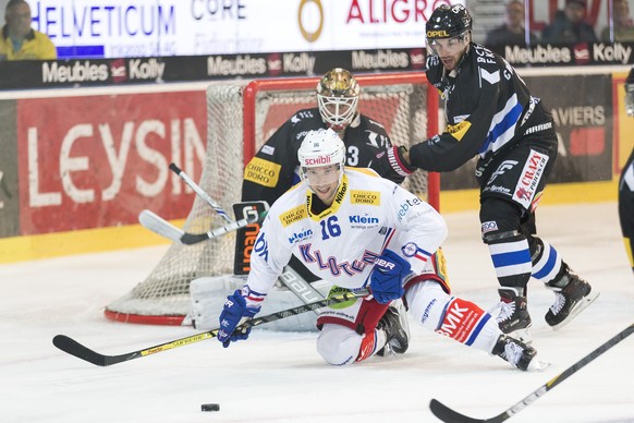 Le joueur de Kloten Daniele Grassi, gauche, lutte pour le puck avec le defenseur fribourgeois Benjamin Chavaillaz, droite, lors du match du championnat suisse de hockey sur glace de National League en ...