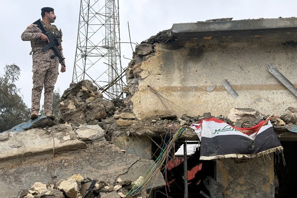 An Iraqi soldier stands guard atop a damaged building at the Iraqi army base in Habbaniyah after it was hit by an airstrike Wednesday, in Anbar province, Iraq, Thursday, March 26, 2026. (AP Photo/Ali  ...