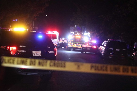 Police and emergency vehicles work at the scene of a shooting at a backyard party, Sunday, Nov. 17, 2019, in southeast Fresno, Calif. Multiple people were shot and at least four of them were killed Su ...