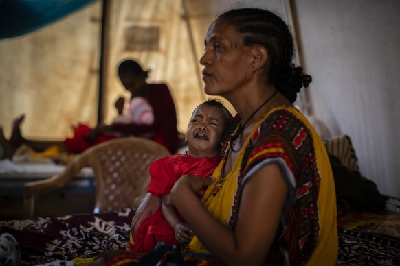 FILE - In this Tuesday May 11, 2021 file photo, Roman Kidanemariam, 35, holds her malnourished daughter, Merkab Ataklti, 22 months old, in the treatment tent of a medical clinic in the town of Abi Adi ...