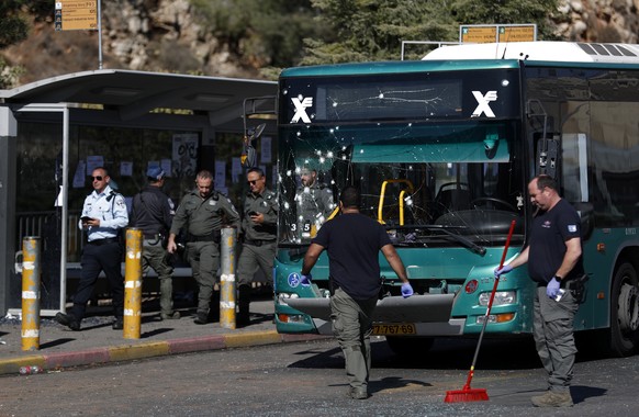 epa10321787 Israeli security forces stand near a damaged bus at the site of explosion at a bus stop at Ramot Junction, near Jerusalem, Israel, 23 November 2022. According to Israeli police, at least 1 ...