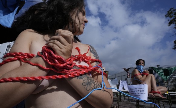 Abortion-rights activists sit gagged and bound during a demonstration outside the National Assembly as lawmakers vote on whether to allow abortion in all cases of rape, in Quito, Ecuador, Thursday, Fe ...