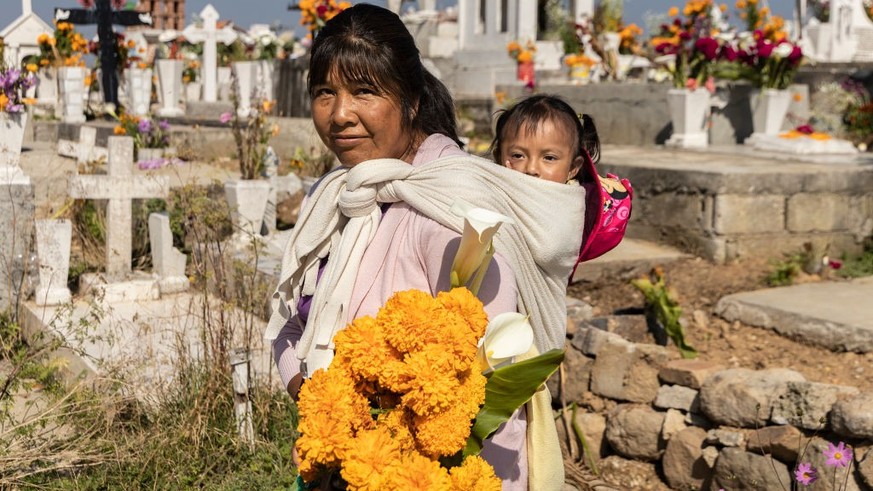 SAN PEDRO ARRIBA, TEMOAYA, MEXICO - NOVEMBER 2: Sonia, who is carrying her granddaughter, poses in the cemetery of San Pedro Arriba during &#039;Day of the Dead&#039; celebrations on November 2, 2022  ...