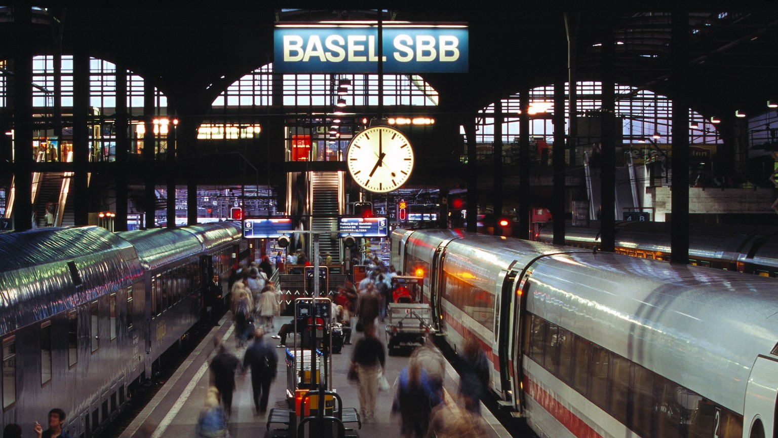 ZUM 75-JAEHRIGEN JUBILAEUM DER SBB BAHNHOFUHR (1944) STELLEN WIR IHNEN FOLGENES BILDMATERIAL ZUR VERFUEGUNG --- Auf dem Bahnsteig im Bahnhof Basel sind Reisende in der Abenddaemmerung auf dem Weg zu i ...