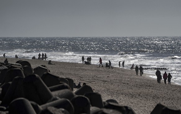 People enjoy the sunny weather at the beach on island Sylt in Westerland, Germany, Saturday, April 3, 2021. (Axel Heimken/dpa via AP)