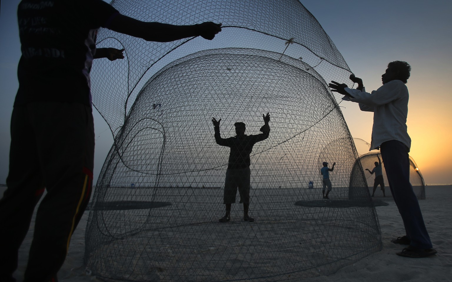 Indian fishermen collect the gargour trap after they repaired them during the sunset of the last day of fishing season at the Jumeirah fishing harbour in Dubai, United Arab Emirates, Friday June 17, 2 ...