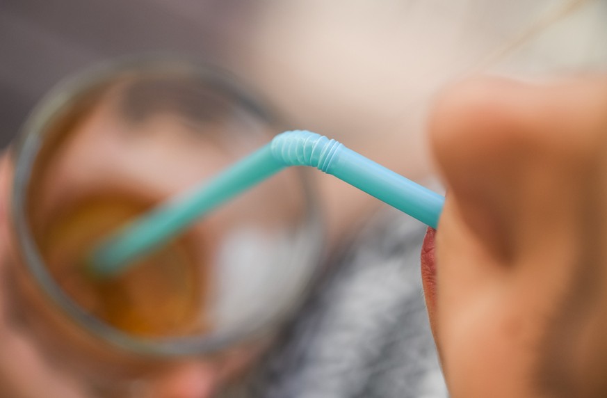 24.05.2018, Brandenburg, Sieversdorf: ILLUSTRATION: Ein Mädchen trinkt mit einem Strohhalm aus Plastik aus einem Glas. Die EU-Kommission präsentiert am 28.05.2018 Pläne zu möglichen Verboten von Einma ...