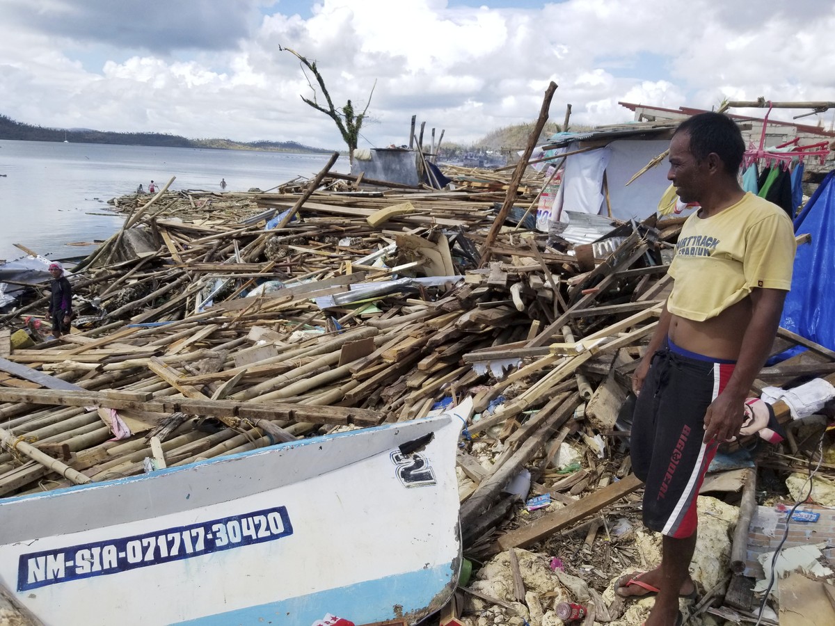 In this photo provided by the Office of the Vice President, a resident looks at toppled trees and structures due to Typhoon Rai in Siargao island, Surigao del Norte, southern Philippines, Sunday Dec.  ...