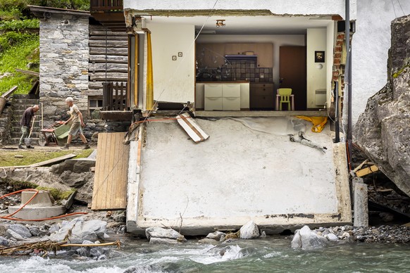 Two men work next to a destroyed house beside the river in Piano di Peccia, in the Maggia Valley, southern Switzerland on Wednesday July 3, 2024. Severe storms and torrential rain over the last weeken ...