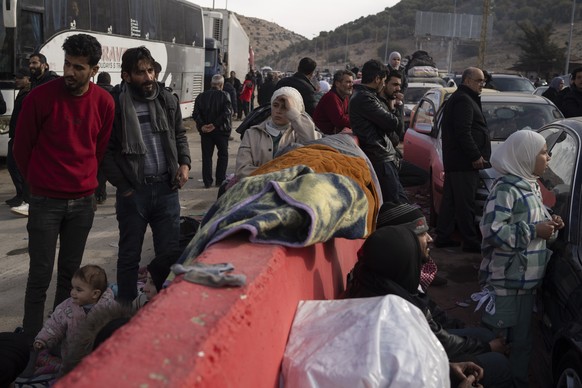 Syrians wait on the road to cross into Lebanon near the Masnaa crossing border, as seen from east Lebanon, Wednesday, Dec. 11, 2024. (AP Photo/Leo Correa)