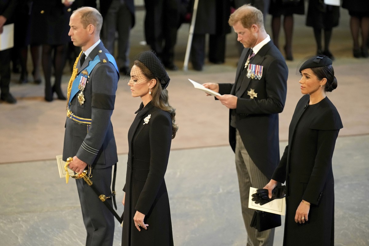 Britain's Prince William, left, Kate, Princess of Wales, second left, Prince Harry, and his wife Meghan, the Duchess of Sussex, right, pay their respects to Queen Elizabeth II as the coffin rests ...