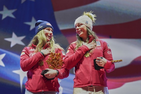 United States' Mikaela Shiffrin, left, and United States' Breezy Johnson listen to the national anthem as they wear their gold medals for a women's team combined event, at the Alpine Sk ...