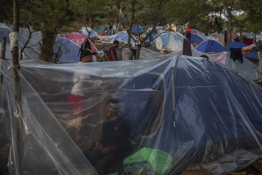 A father and son from Syria stand inside their makeshift tent near the refugee and migrant camp at the Greek island of Samos on Wednesday, Sept. 25, 2019. The refugee and migrant camp of Samos island  ...