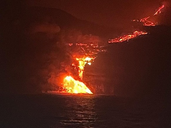 epa09494545 A handout photo made available by the Spanish Institute of Oceanography showing Lava flow from the Cumbre Vieja volcanic eruption in La Palma reaching the sea in an area of cliffs next to  ...