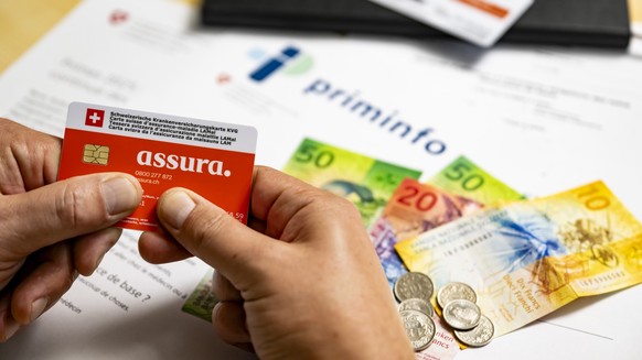 Une illustration pour la hausse des primes d&#039;assurance-maladie, montre une carte suisse d&#039;assurance-maladie LAMal (KVG) de l&#039;assurance Assura, devant des billets de banque suite a l&#03 ...