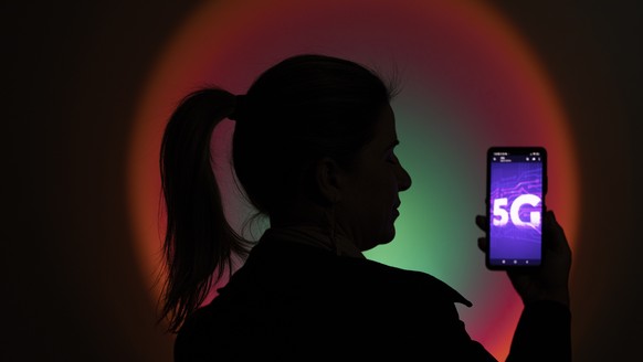 epa10054966 A woman holds a cell phone with an image of the new 5G technology, in Brasilia, Brazil, 06 July 2022. The fifth generation of mobile internet (5G) is activated this Wednesday in Brazil. Br ...