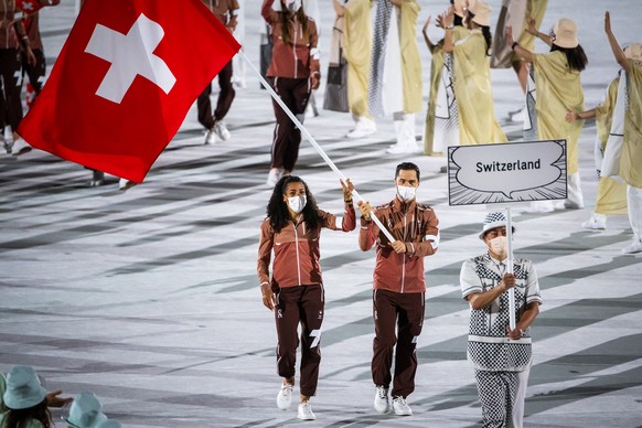 Switzerland&#039;s flag-bearers sprinter Mujinga Kambundji and epee fencer Max Heinzer celebrate during the opening ceremony of the 2020 Tokyo Summer Olympics at the National Stadium in Tokyo, Japan,  ...