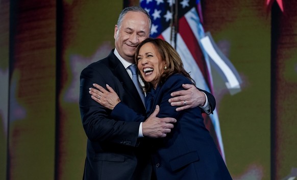 epa11561035 Democratic presidential nominee and US Vice President Kamala Harris (R) and her husband Second Gentleman Doug Emhoff (L) embrace on stage after she spoke during the final night of the Demo ...