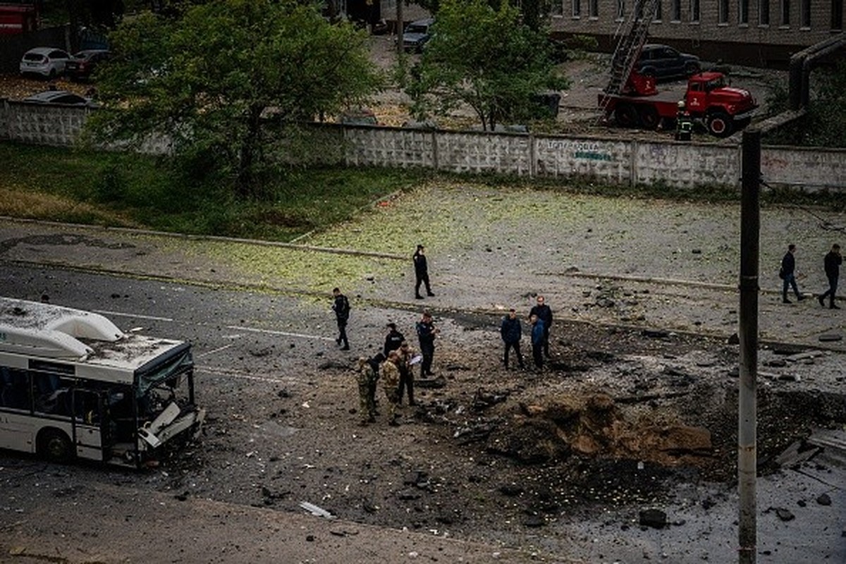 TOPSHOT - Investigators examine a crater next to a damaged bus, following a missile strike in Dnipro on October 10, 2022, amid Russia's invasion of Ukraine. - The head of the Ukrainian military s ...