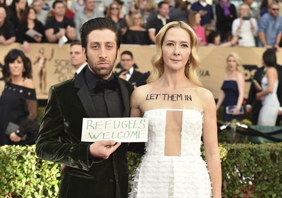 Simon Helberg, left, and Jocelyn Towne display protest signs against the U.S. policy of temporarily barring refugees and citizens of seven predominantly Muslim countries, at the 23rd annual Screen Act ...