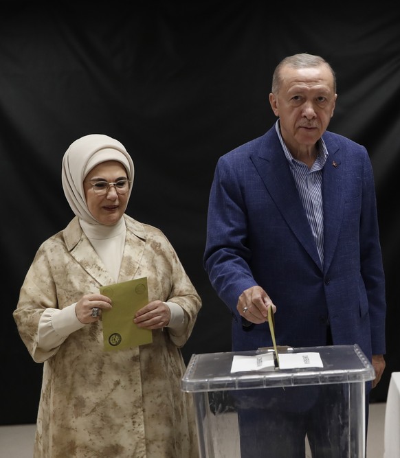 epaselect epa10659526 Turkish President Recep Tayyip Erdogan casts his ballot as his wife Emine Erdogan stands next to him at a polling station during the second round of the presidential election in  ...