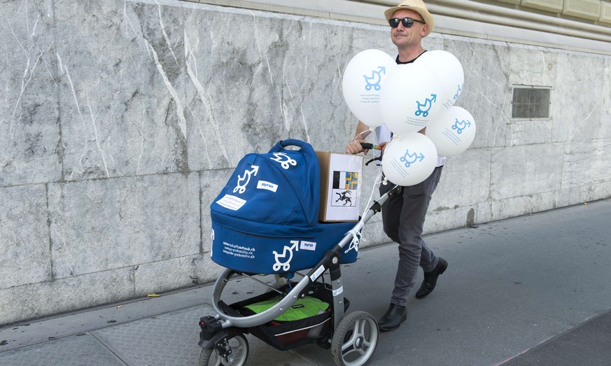 ARCHIVBILD ZUR MELDUNG, DASS DER BUNDESRAT GEGEN VIER WOCHEN VATERSCHAFTSURLAUB IST --- Ein Aktionsteilnehmer kommt mit einer Schachtel mit Unterschriften aus dem Kanton Graubuenden und einem Kinderwa ...