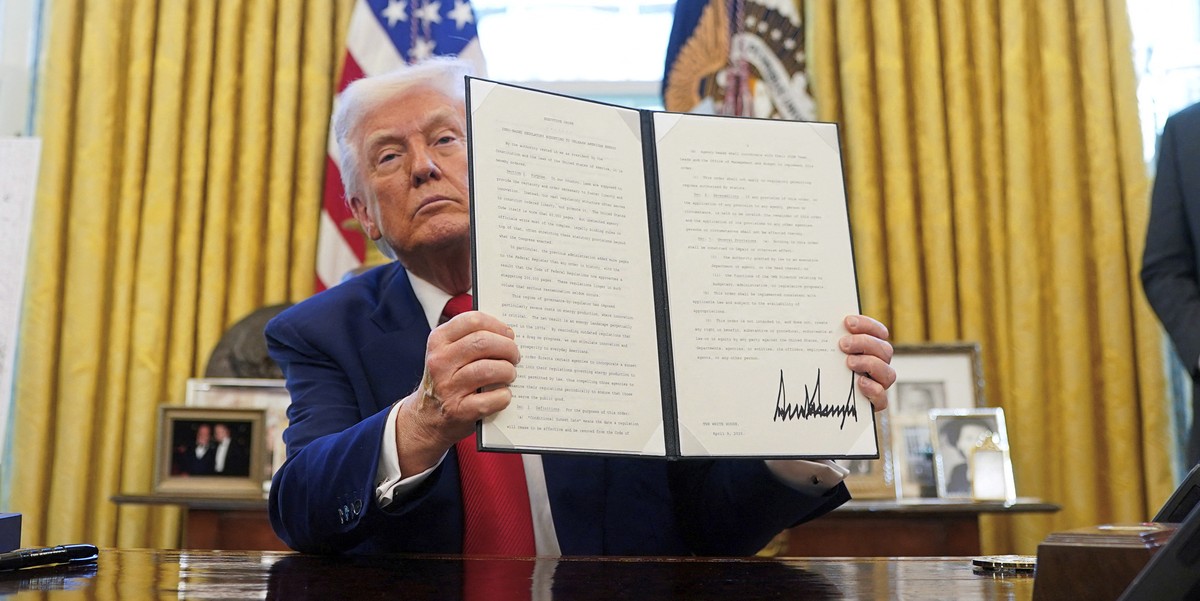 President Donald Trump holds a signed executive order in the Oval Office of the White House Wednesday, April 9, 2025, in Washington. (Pool via AP)
Trump