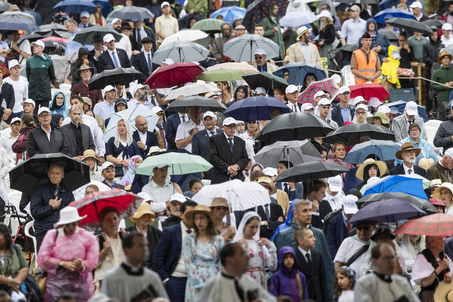 epa13077596 Worshippers protect themselves with umbrellas from the heavy rain during the episcopal consecration of Catholic priests as part of a pontifical mass organized by the Society of Saint Pius  ...