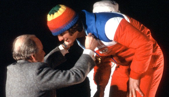U.S. speed skater Eric Heiden bends to receive his fifth gold medal from Olympic official during awards ceremony at Lake Placid,N.Y. Feb.23,1980. Heiden took the gold for his victory in the 10,000- me ...