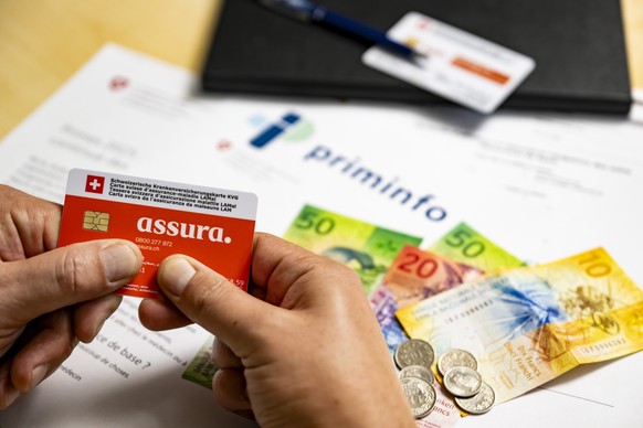 Une illustration pour la hausse des primes d&#039;assurance-maladie, montre une carte suisse d&#039;assurance-maladie LAMal (KVG) de l&#039;assurance Assura, devant des billets de banque suite a l&#03 ...