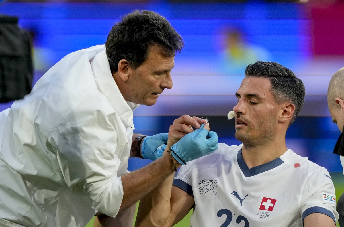 Switzerland's Fabian Schar, right, gets treatment during a Group A match between Scotland and Switzerland at the Euro 2024 soccer tournament in Cologne, Germany, Wednesday, June 19, 2024. (AP Pho ...