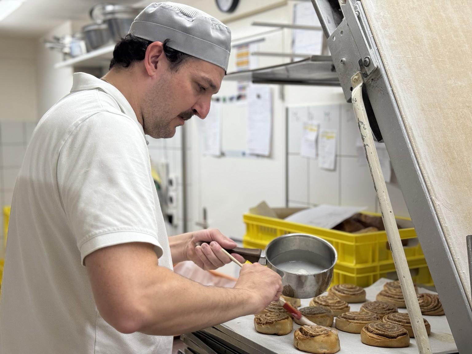 Nils bestreicht Zimtschnecken mit Zuckerguss