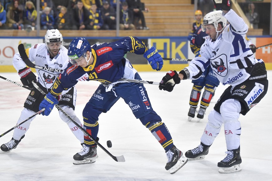 Die Fribourger Ryan Gunderson (USA), links und Samunel Walser nehmen den Davoser Rapahael Prassl in die Zange, im Eishockey-Qualifikationsspiel der National League zwischen dem HC Davos und dem HC Fri ...