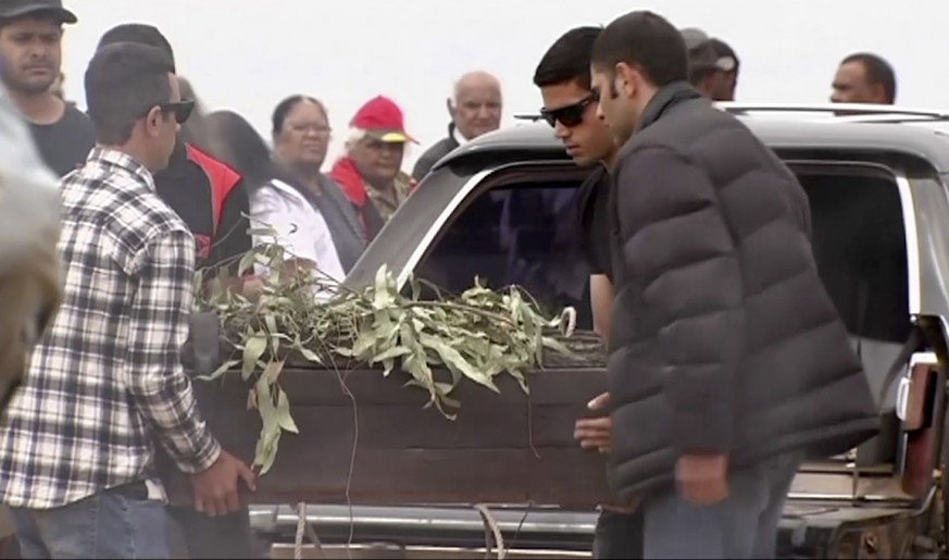 In this image made from video, the oldest human remains in a coffin are unloaded from a hearse for a traditional ceremony in Lake Mungo, Australia, Friday, Nov. 17, 2017. The human remains found in Au ...