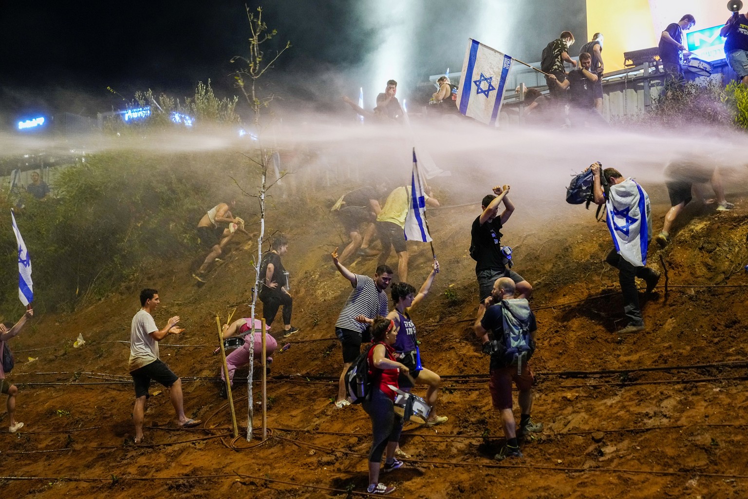EDS NOTE: OBSCENITY - Israeli police use a water cannon to disperse demonstrators blocking a highway during a protest against plans by Prime Minister Benjamin Netanyahu&#039;s government to overhaul t ...