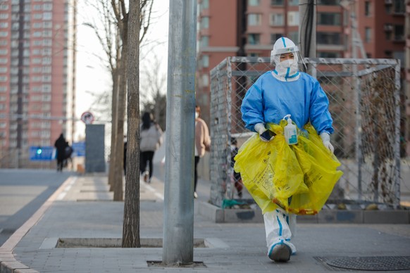 epa10353328 A volunteer health worker walks on the street in Beijing, China, 07 December 2022. According to the official data released in April of 2022, that only around 20 percent of over-80s had rec ...