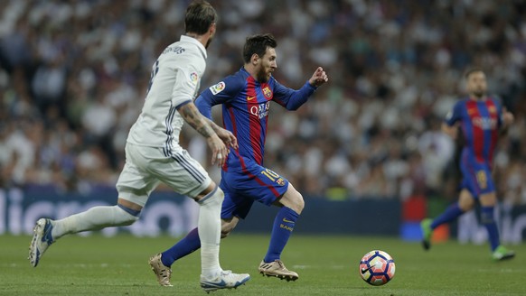 Barcelona&#039;s Lionel Messi, center, runs with the ball past Real Madrid&#039;s Sergio Ramos during a Spanish La Liga soccer match between Real Madrid and Barcelona, dubbed &#039;el clasico&#039;, a ...