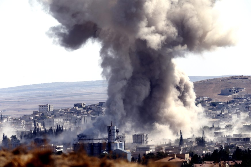 epa04437095 A picture taken from Turkey shows smoke rises after an airstrike by an allegeded alliance war plane on Islamic State targets in the west of Kobane, Syria, where Kurdish fighters YPG are tr ...