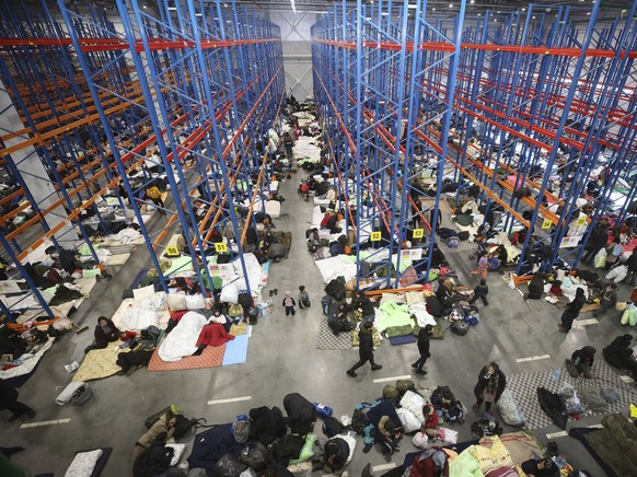 Migrants settle for the night in the logistics center in the checkpoint &quot;Kuznitsa&quot; at the Belarus-Poland border near Grodno, Belarus, on Thursday, Nov. 18, 2021. A plane carrying migrants ba ...