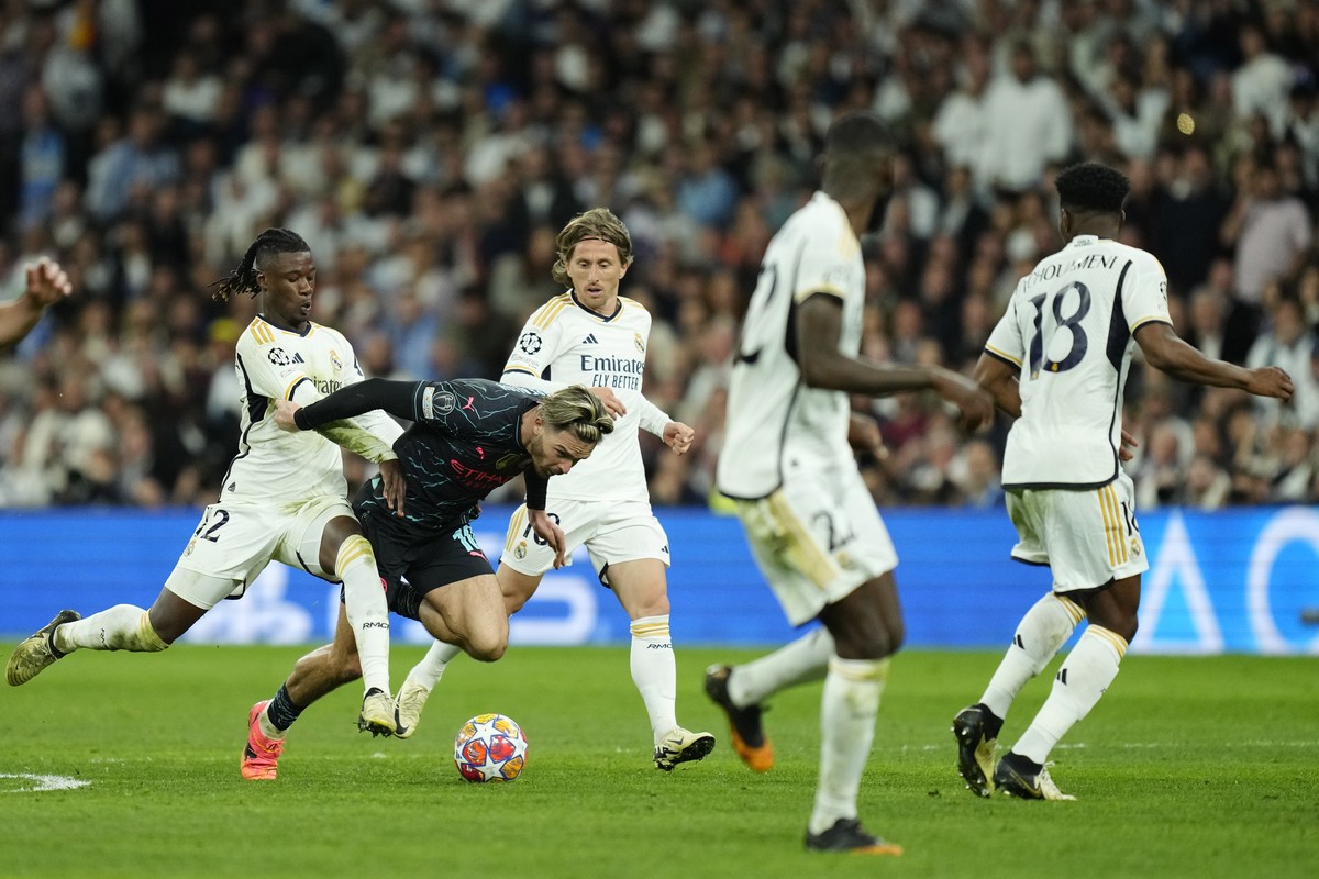 Manchester City's Jack Grealish, second left, is challenged by Real Madrid's Eduardo Camavinga, left, and Real Madrid's Luka Modric, center, during the Champions League quarterfinal fir ...