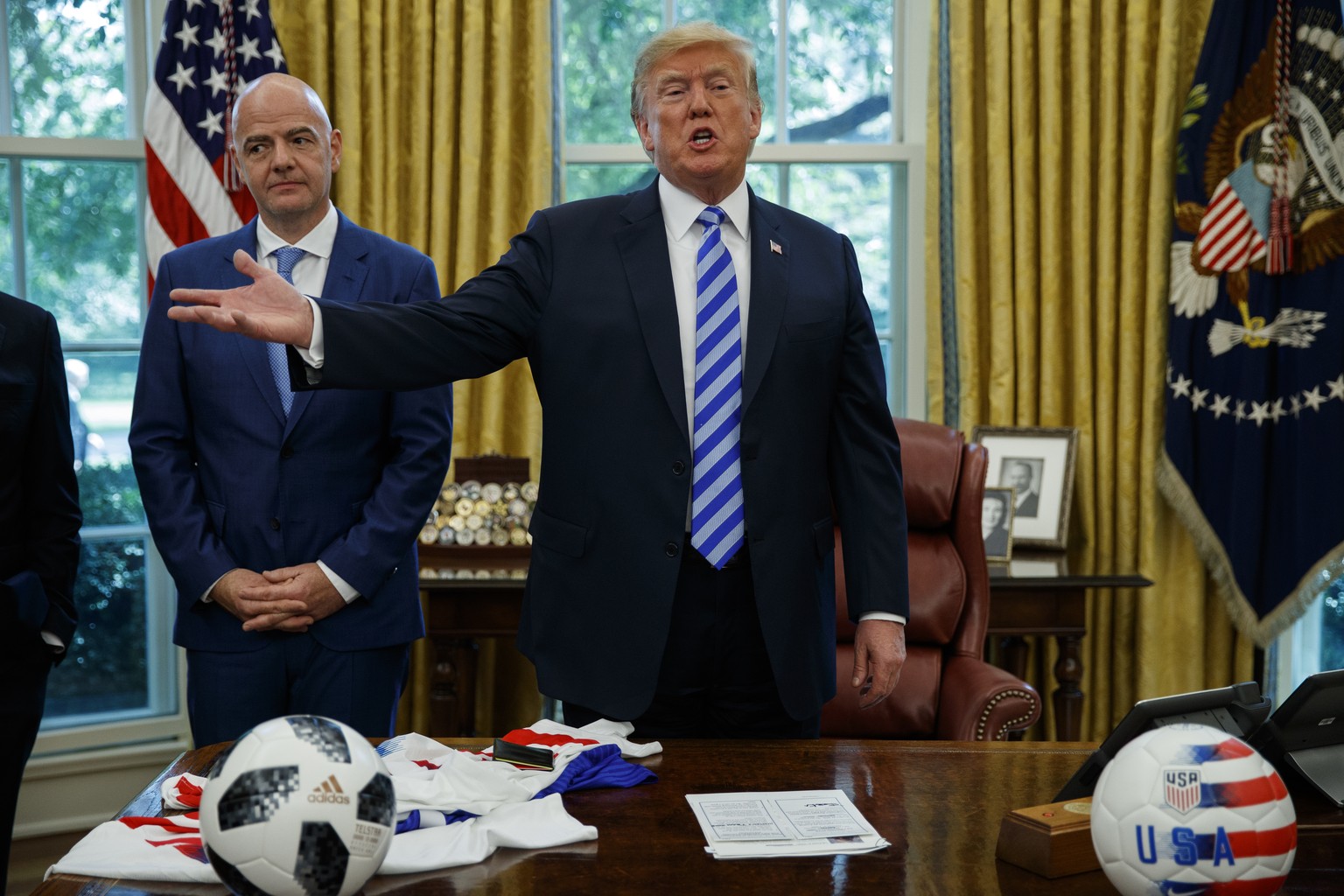 FIFA president Gianni Infantino, left, watches as President Donald Trump speaks to reporters during a meeting in the Oval Office of the White House, Tuesday, Aug. 28, 2018, in Washington. (AP Photo/Ev ...