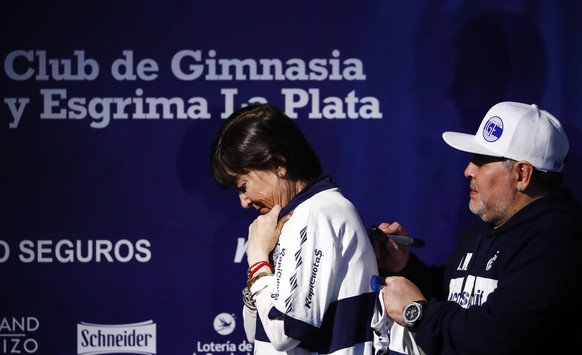 Former soccer great Diego Maradona signs the jersey of Giselle Fernandez, the sister of former Argentine President Cristina Fernandez de Kirchner, during a news conference after Maradona's presen ...