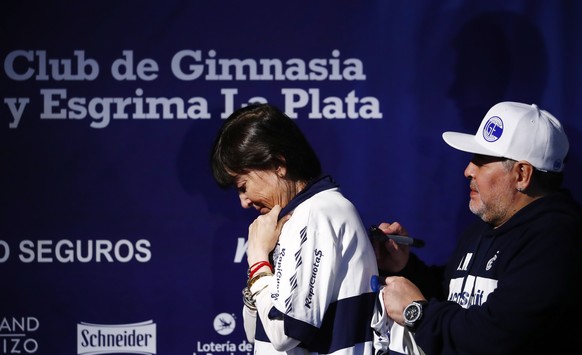 Former soccer great Diego Maradona signs the jersey of Giselle Fernandez, the sister of former Argentine President Cristina Fernandez de Kirchner, during a news conference after Maradona&#039;s presen ...